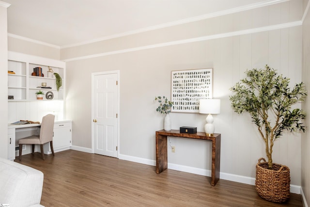 office space with built in desk, crown molding, baseboards, and wood finished floors