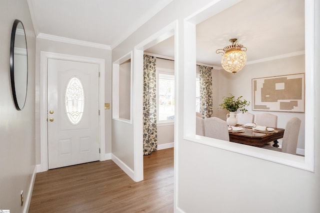 entryway featuring crown molding, wood finished floors, baseboards, and a chandelier