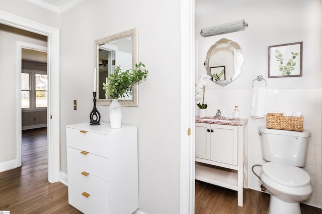 bathroom with vanity, wood finished floors, ornamental molding, tile walls, and toilet