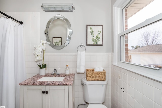 full bathroom with a wainscoted wall, toilet, tile walls, and vanity