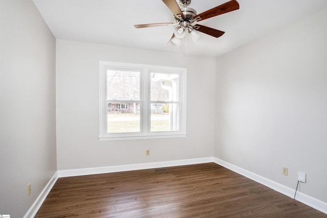 spare room featuring dark wood finished floors, visible vents, and baseboards