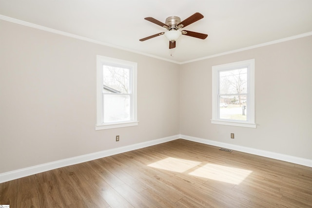 empty room featuring a healthy amount of sunlight, visible vents, and baseboards