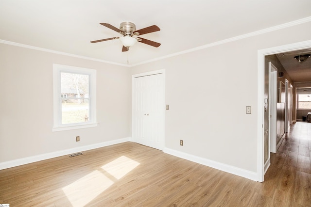 unfurnished room featuring visible vents, crown molding, baseboards, wood finished floors, and a ceiling fan