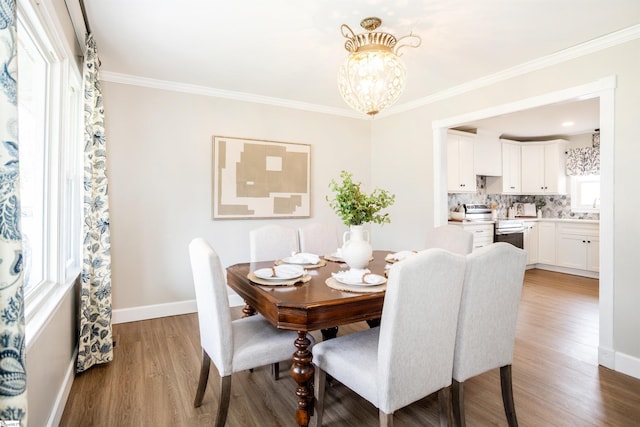 dining space featuring baseboards, crown molding, an inviting chandelier, and wood finished floors