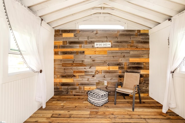 sitting room featuring hardwood / wood-style floors, vaulted ceiling with beams, and wood walls