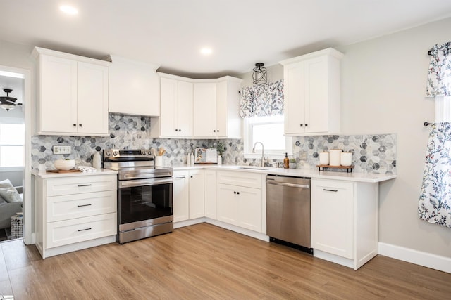 kitchen with white cabinets, appliances with stainless steel finishes, light countertops, and a sink