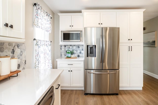 kitchen featuring light wood-type flooring, backsplash, white cabinetry, appliances with stainless steel finishes, and light countertops