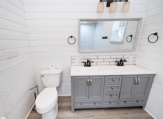 full bath with a sink, toilet, wood finished floors, and double vanity