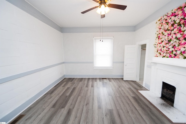 unfurnished living room with a fireplace with flush hearth, wood finished floors, baseboards, and ceiling fan