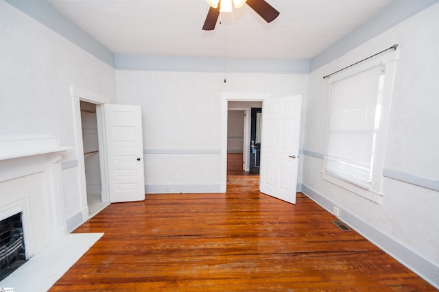 unfurnished bedroom with visible vents, a fireplace with flush hearth, baseboards, and wood finished floors