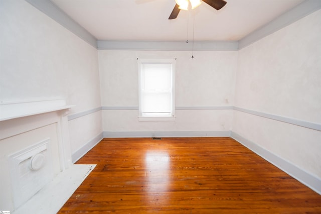 unfurnished room with a ceiling fan, wood finished floors, and baseboards