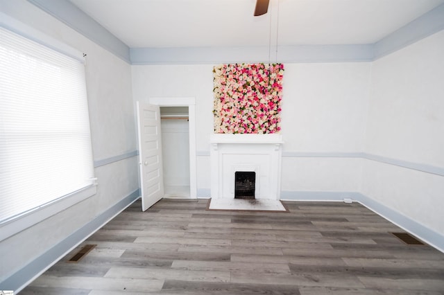 unfurnished living room with visible vents, a healthy amount of sunlight, and wood finished floors