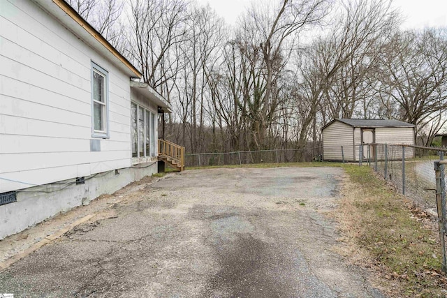 view of yard featuring aphalt driveway, an outdoor structure, and fence