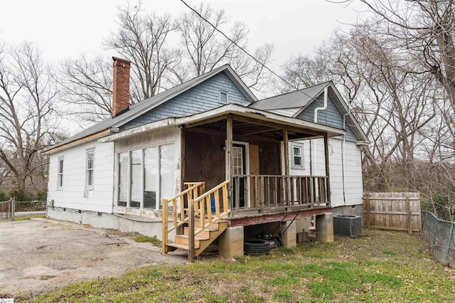 view of front of property featuring fence, covered porch, a chimney, crawl space, and central air condition unit