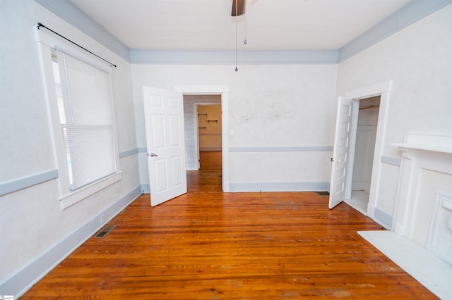 interior space featuring visible vents, a ceiling fan, baseboards, and wood finished floors