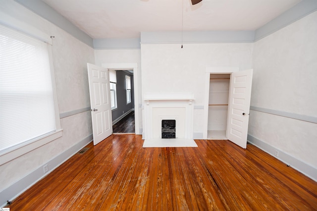 unfurnished living room with baseboards and hardwood / wood-style flooring