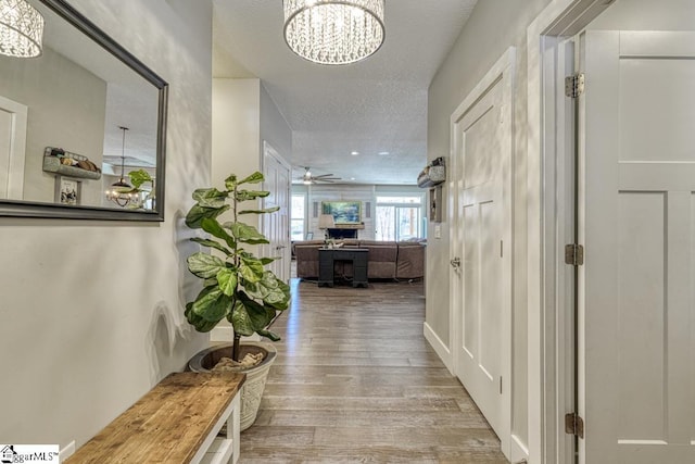 hallway with a notable chandelier, a textured ceiling, and wood finished floors