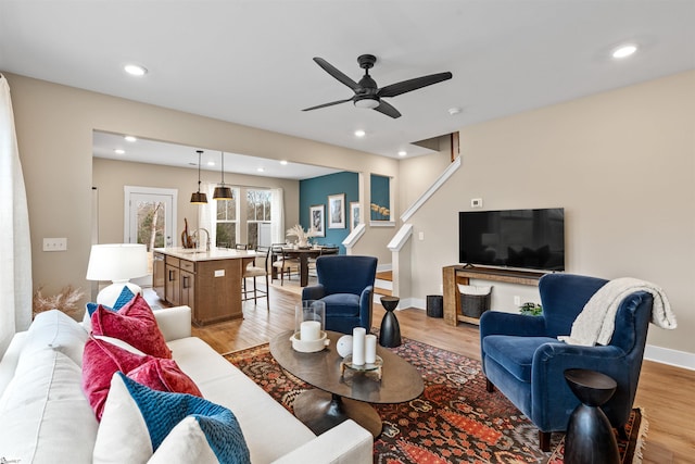 living area with stairs, recessed lighting, baseboards, and light wood finished floors