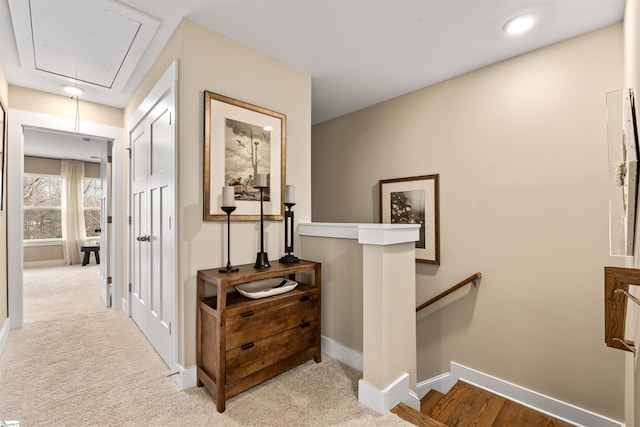 corridor featuring an upstairs landing, attic access, baseboards, and carpet floors