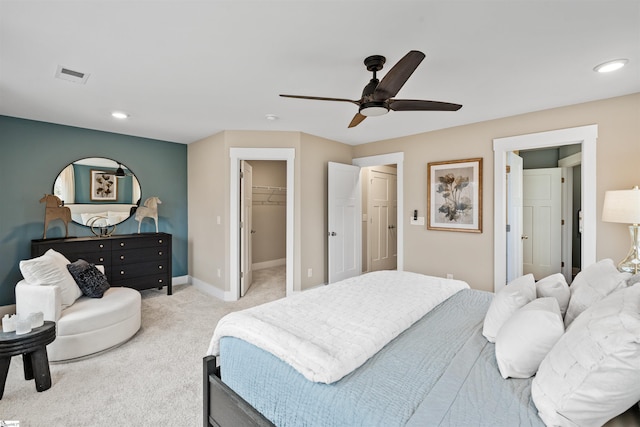 bedroom with visible vents, a walk in closet, baseboards, ceiling fan, and carpet flooring