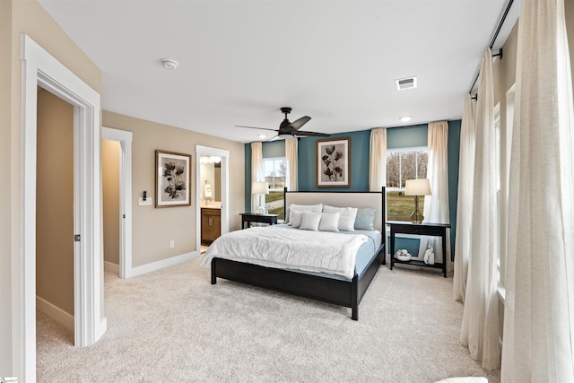 bedroom with a ceiling fan, baseboards, visible vents, ensuite bath, and light carpet