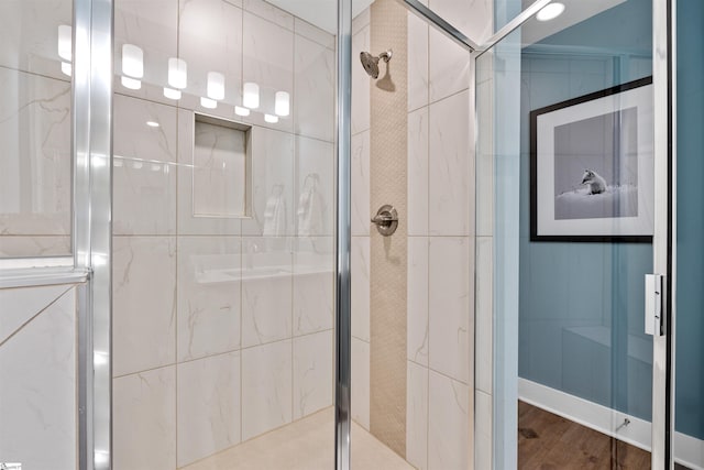 bathroom with wood finished floors and a shower stall