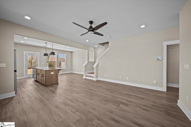 living room featuring recessed lighting, stairs, baseboards, and wood finished floors