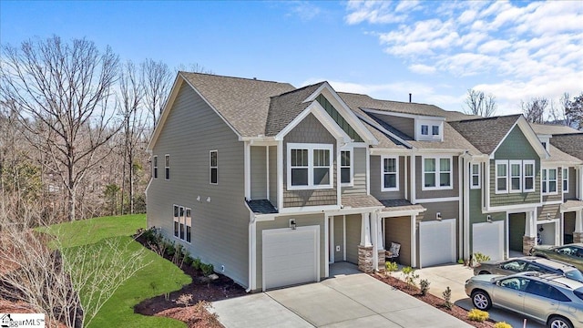 view of front of house featuring an attached garage, driveway, and a shingled roof