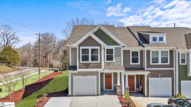 view of front facade with board and batten siding, a garage, driveway, and a shingled roof