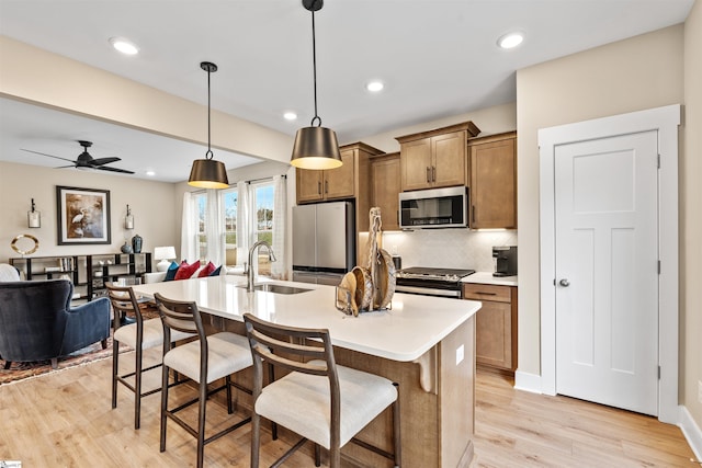 kitchen featuring brown cabinets, a sink, stainless steel appliances, a breakfast bar area, and decorative backsplash