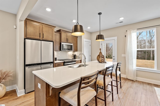 kitchen featuring a breakfast bar area, visible vents, a sink, decorative backsplash, and stainless steel appliances