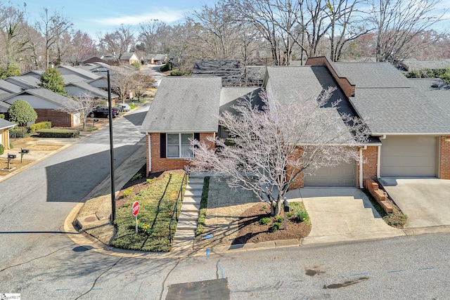 view of front of home featuring a residential view, brick siding, concrete driveway, and an attached garage