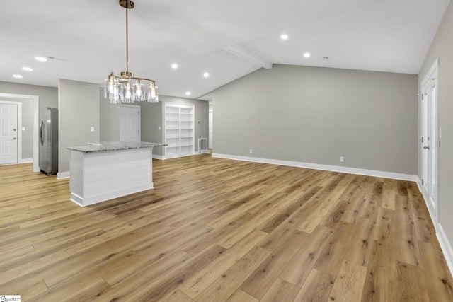 kitchen with a kitchen island, vaulted ceiling with beams, baseboards, freestanding refrigerator, and light wood-style floors