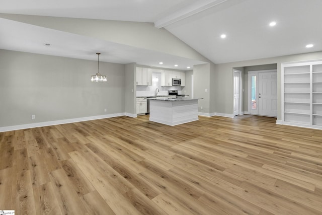 kitchen featuring a sink, open floor plan, stainless steel appliances, white cabinets, and light wood finished floors