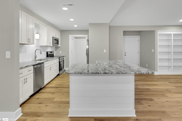 kitchen with visible vents, light wood finished floors, a sink, white cabinets, and appliances with stainless steel finishes