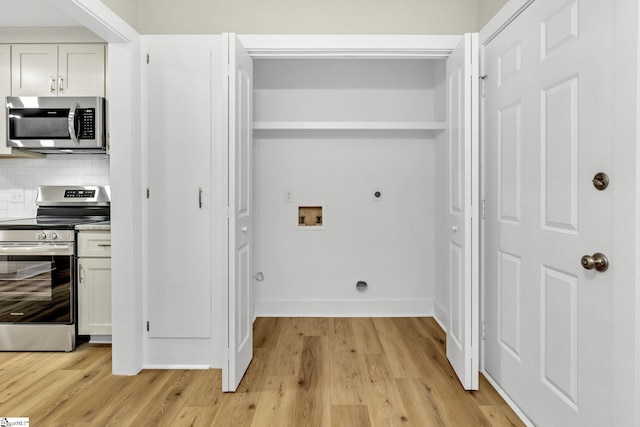 clothes washing area with hookup for a washing machine, baseboards, hookup for an electric dryer, laundry area, and light wood-style flooring