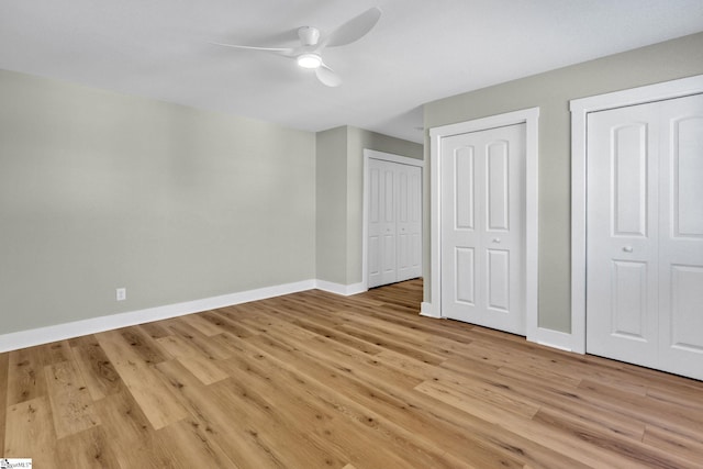 unfurnished bedroom featuring baseboards, multiple closets, light wood finished floors, and ceiling fan