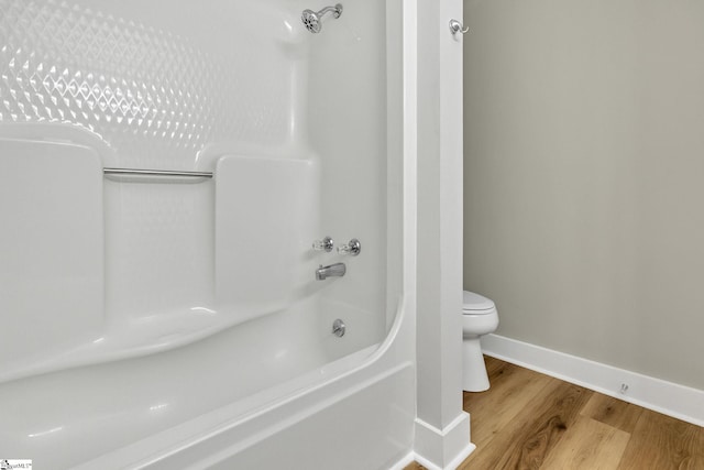 full bath featuring shower / bath combination, baseboards, toilet, and wood finished floors