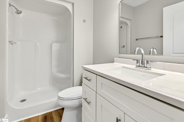 bathroom featuring vanity, toilet, wood finished floors, and a shower stall