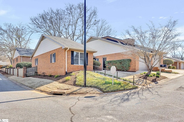 view of front of house with concrete driveway, an attached garage, fence, and brick siding