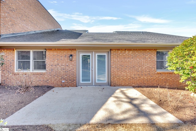 back of house with brick siding, a patio area, and a shingled roof