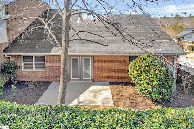 rear view of property with a patio, brick siding, and a shingled roof