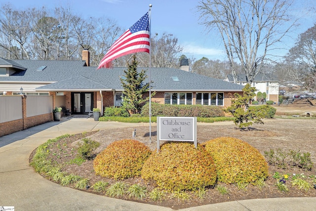 view of front of house with a shingled roof, fence, brick siding, and a chimney