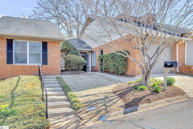 view of front facade featuring driveway, brick siding, an attached garage, and a shingled roof