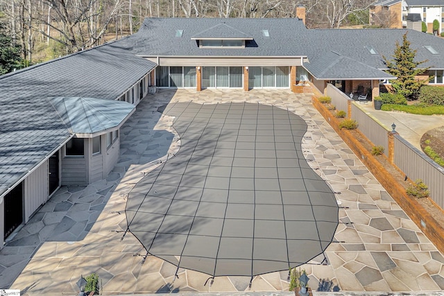 exterior space with a patio area, a shingled roof, a fenced backyard, and brick siding