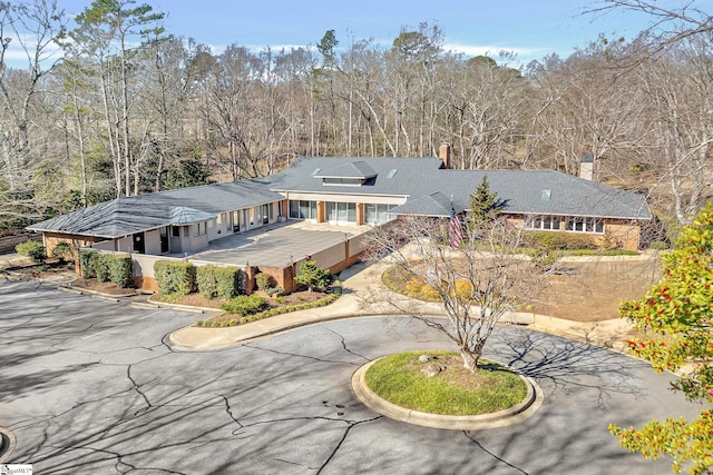 back of property with a chimney and curved driveway