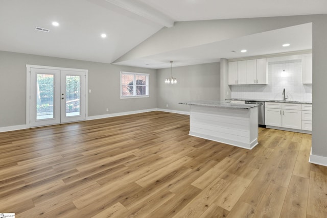 kitchen featuring light wood finished floors, lofted ceiling with beams, white cabinets, dishwasher, and tasteful backsplash