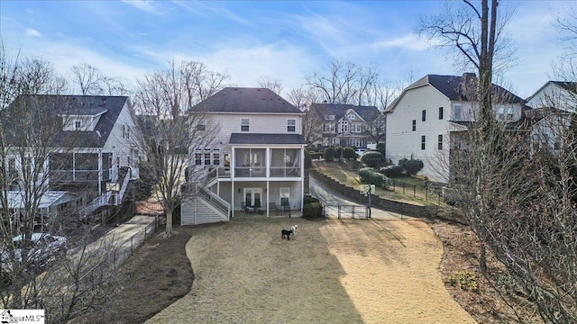 back of property with stairway, fence, a lawn, and a sunroom