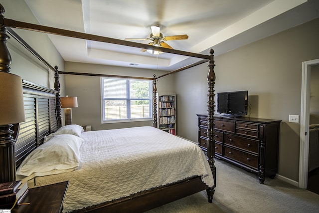 carpeted bedroom featuring a raised ceiling, baseboards, and ceiling fan