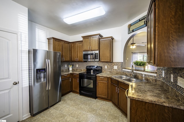 kitchen featuring a sink, arched walkways, backsplash, and appliances with stainless steel finishes